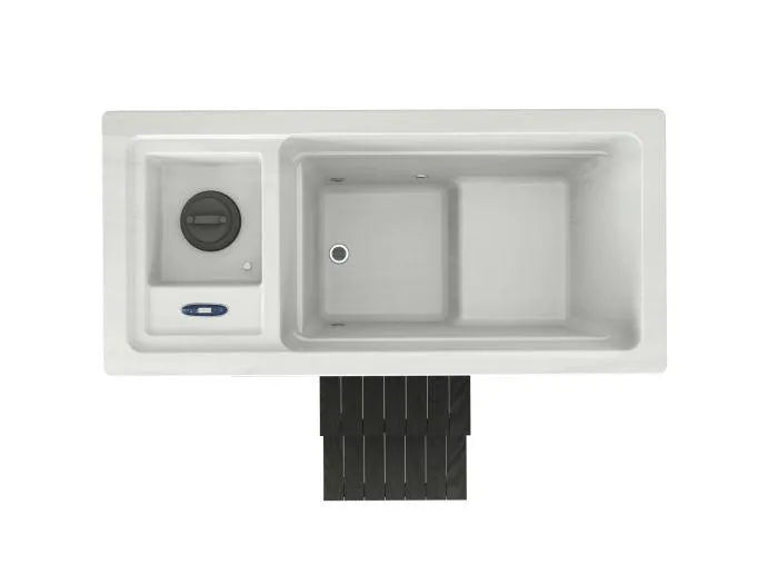 Top-down view of a white kitchen sink setup, featuring a large rectangular basin, a smaller secondary basin with a drain, and a built-in garbage disposal on the left side. Below the sink, there is a black dish rack perfect for draining items after cold water immersion in the Chillax Ice Bath & Chill Tub Professional affordable wellness Ice Baths & Plunge Pool by Chill Tubs.
