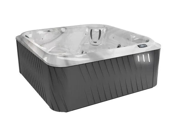 A luxurious, empty J-275 CLASSIC LARGE HOT TUB WITH LOUNGE SEAT - NEW MODEL by Jacuzzi with a sleek, modern design. The hot tub features a dark grey exterior, white interior, and multiple seating positions with jets for a personalised hydromassage experience. A control panel is visible on the rim for easy access to settings.