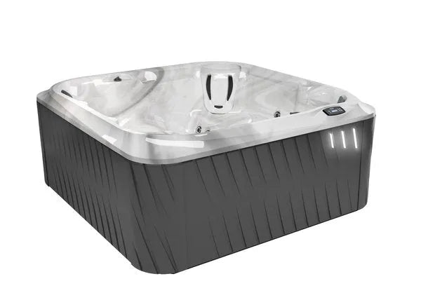 A modern, square J-235 CLASSIC HOT TUB WITH LOUNGE SEAT - NEW MODEL by Jacuzzi with a sleek, dark gray exterior and a white, marble-patterned interior. The tub features built-in seating and multiple jets for indulgent hydromassage. An electronic control panel is visible on the outer edge.