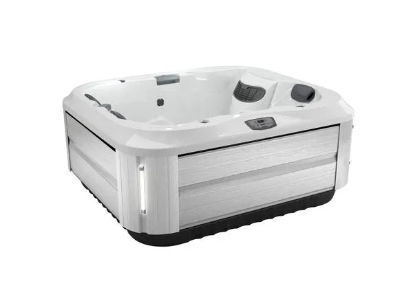 A modern, square J-315 COMFORT HOT TUB WITH LOUNGER FOR SMALL SPACES by Jacuzzi with a white exterior and black base. It features built-in headrests, a digital control panel, and multiple PowerPro® jets for enhanced hydrotherapy benefits. The tub’s sleek interior is white, embodying a contemporary design.