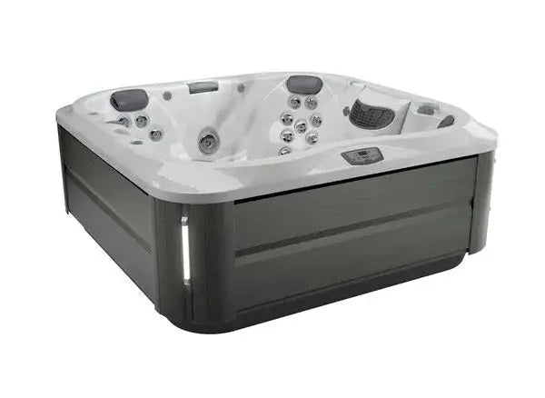 A modern, square hot tub with multiple jets featuring Jacuzzi® PowerPro® jet technology and seating for several people. The J-335 COMFORT HOT TUB WITH OPEN SEATING by Jacuzzi has a sleek design with a grey exterior and a white interior. Control panel, SmartTub™ System, headrests, and ProClear® filtration system are visible.