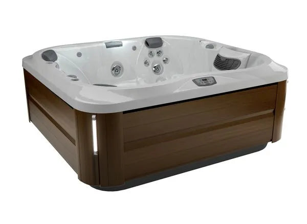 A high-end outdoor Jacuzzi J-355 HOT TUB WITH COMFORT LOUNGE SEATING & COOL DOWN SEAT with a sleek wooden exterior. The white interior features multiple hydrotherapy jets and controls, offering seating for several people. The contemporary design includes integrated lighting, a digital control panel on the side, and a ProClear filtration system for clean relaxation.