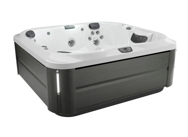 A sleek, modern Jacuzzi J-355 HOT TUB WITH COMFORT LOUNGE SEATING & COOL DOWN SEAT with a white interior and dark gray exterior. It features multiple hydrotherapy jets and a small control panel on the inner edge. The design includes built-in seats with headrests, offering a contemporary look enhanced by the ProClear filtration system.