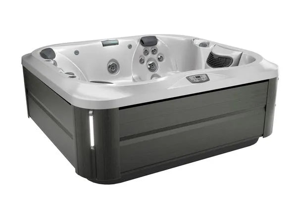 A square, modern Jacuzzi J-355 HOT TUB WITH COMFORT LOUNGE SEATING & COOL DOWN SEAT with a sleek, dark gray exterior and a white interior featuring multiple hydrotherapy jets and seating areas. A digital control panel is visible on the top edge next to a built-in speaker system and ProClear filtration system for crystal-clear water.