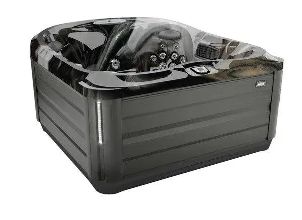 A square, gray J-445™ OPEN SEATED HOT TUB WITH INFRARED & RED LIGHT THERAPY with a sleek, modern design is shown. Featuring Jacuzzi PowerPro jets for exceptional hydrotherapy, it has multiple seating areas, a control panel on the side, and a decorative exterior. The hot tub has a partially transparent cover displaying the interior seating.