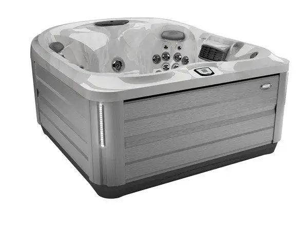 A modern hot tub with a sleek, light gray, wood-paneled exterior. It features multiple Jacuzzi PowerPro jets, a digital control panel, and LED lighting. The interior is designed with comfortable seating for several people, offering an exceptional hydrotherapy experience. The J-445™ OPEN SEATED HOT TUB WITH INFRARED & RED LIGHT THERAPY by Jacuzzi is truly exceptional.