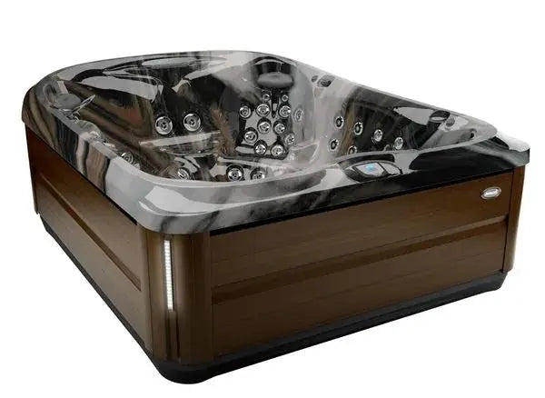 A luxurious, dark marble J-495™ DESIGNER ENTERTAINER'S HOT TUB WITH INFRARED & RED LIGHT THERAPY - NEW MODEL by Jacuzzi with wooden paneling exterior, showcasing multiple PowerPro jets and seating areas for relaxation. The hot tub includes an ergonomic design with various controls and features for a hydromassage experience akin to a spa.