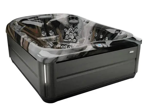 A modern, square Jacuzzi J-495™ DESIGNER ENTERTAINER'S HOT TUB WITH INFRARED & RED LIGHT THERAPY - NEW MODEL with sleek black exterior panels. The tub is filled with water and features multiple PowerPro jets and seating areas, emitting steam that indicates warmth. The design is contemporary, focusing on relaxation and offering a therapeutic hydromassage experience.