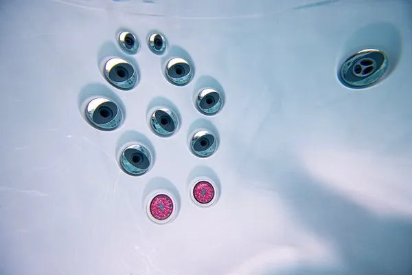 Jets and lights are visible inside an empty **Jacuzzi - J-LXL Hot Tub**, with ten circular jets in chrome fixtures aligned in two rows. Among them, two jets emit a pinkish-red light, offering a touch of red light therapy that illuminates the white surface of the tub's interior.