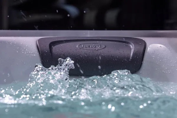 A close-up of a Jacuzzi - J-LXL Hot Tub filled with bubbling water. The image shows the water's surface churning and splashing near a cushioned headrest labeled "Jacuzzi," highlighting the soothing effects of hydrotherapy. The headrest extends above the waterline at the back of the tub.