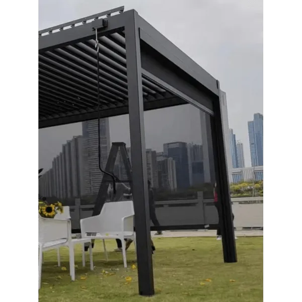 A modern, black pergola with an adjustable louvered roof and Sunhut Manual Blind (4M) by Sunbeach Spas stands on a grassy rooftop, overlooking a city skyline with tall buildings. Underneath the pergola are white chairs and a table with a small plant. The scene is serene and contemporary, offering outdoor privacy in urban elegance.