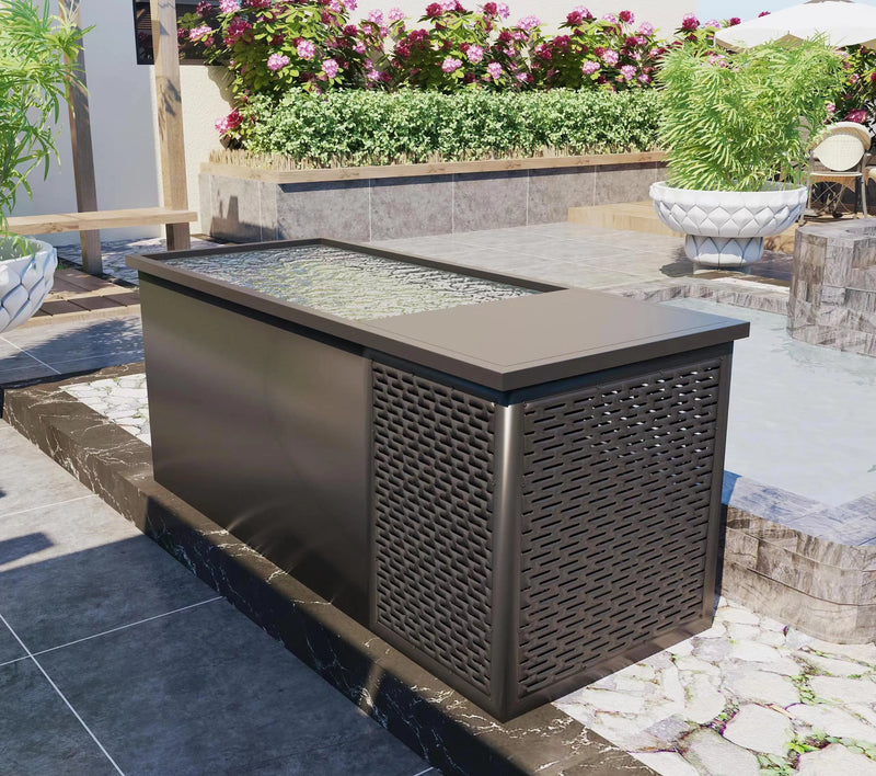 A sleek, rectangular outdoor planter, reminiscent of Chill Tubs - Professional affordable Ice Baths ideal for gym fanatics by Chill Tubs, is positioned in a modern garden. Filled with water, it offers a reflective surface and features a perforated design on one side. Surrounded by lush greenery, flowering plants, and stone pathways, it invites cold water therapy enthusiasts to unwind.