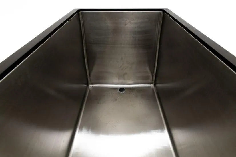 A close-up view of a rectangular stainless steel sink taken from the interior, showcasing its smooth, reflective surfaces and a small drain hole at the bottom. The sink is clean and has a minimalist design, much like those found in Chill Tubs - Professional affordable Ice Baths ideal for gym fanatics by Chill Tubs designed for cold water therapy.