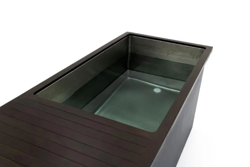 A large, modern, rectangular bathtub with dark edges is filled with clear water, ideal for cold water therapy. The tub has a sleek design, featuring clean lines and a recessed area for bathing. Part of the tub's surface appears to have a wooden or slatted finish. This is the Chill Tubs - Professional affordable Ice Baths ideal for gym fanatics by Chill Tubs.