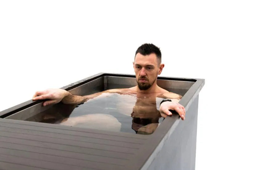 A man with a beard and short hair sits immersed in a Chill Tubs - Professional affordable Ice Baths ideal for gym fanatics by Chill Tubs, with only his upper body visible above the cold water. He appears focused and calm. The background is plain white.