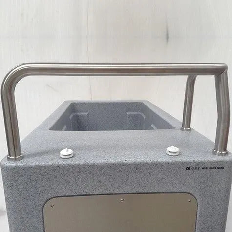 A close-up view of a gray, rectangular industrial device with a stainless steel handlebar attached to the top. Resembling equipment used in athlete recovery, the CryoSpa Sport - Cold Water Ice Bath by CET CryoSpas has a metal plate and button-like features on its surface, set against a plain background.