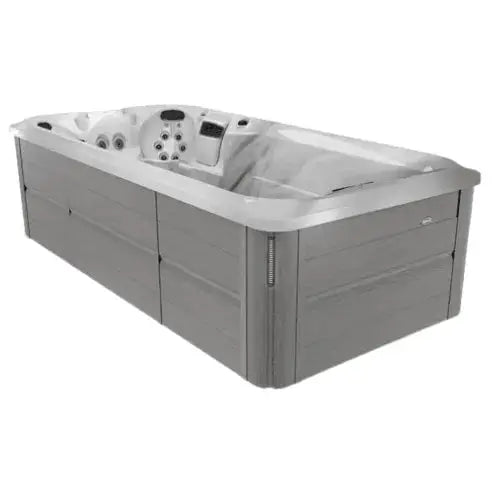 A rectangular, modern J-16 Powerpro™ Swim Spa with a sleek, grey exterior and multiple built-in Jacuzzi PowerPro jets is shown. The Hot Tub Liverpool product has a spacious interior designed for comfort and relaxation. Hydromassage seats and headrests are visible, indicating a well-equipped spa experience.