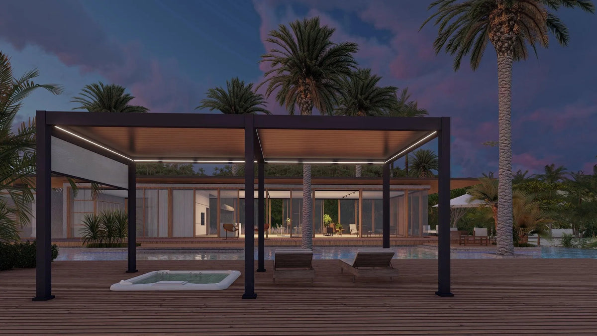 A modern outdoor lounge area by a pool at dusk, featuring a sleek Jacuzzi® Pergola 3600 with a motorised louvre roof and integrated LED strips. Two lounge chairs and a small hot tub sit on the wooden deck. Palm trees and the contemporary glass-fronted house are visible in the background.