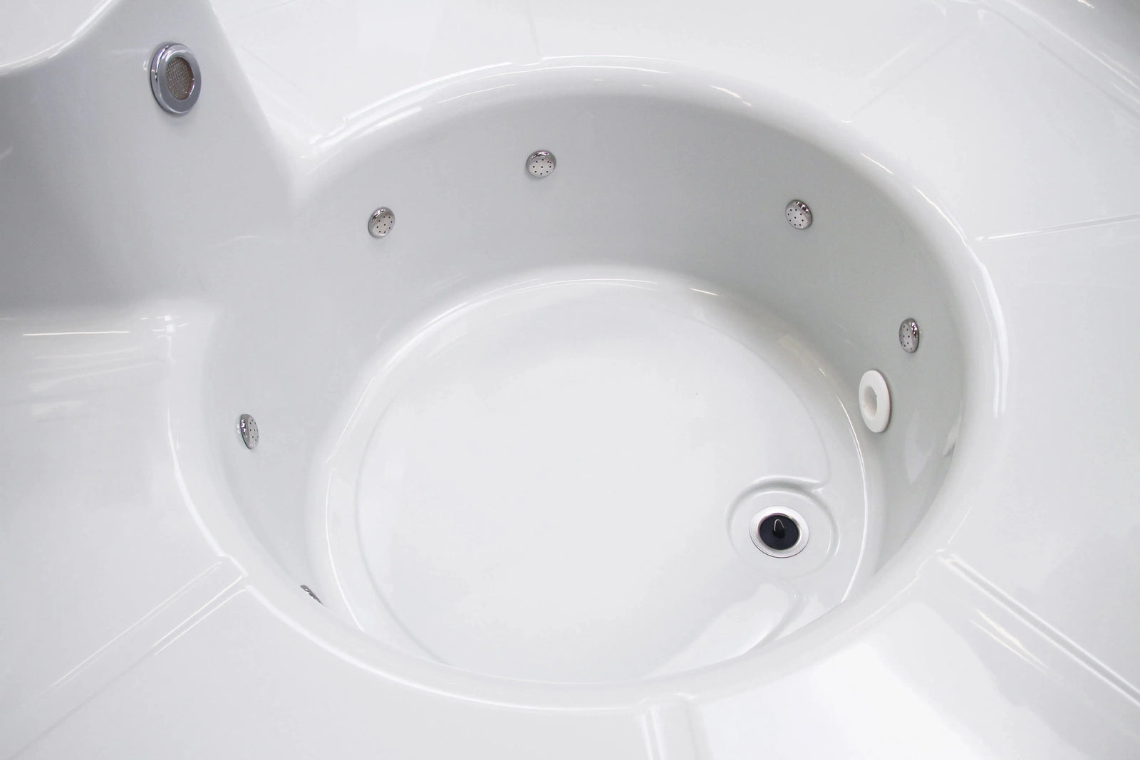 Close-up view of an empty, white jacuzzi tub with multiple jets around its interior. The smooth, clean surface reflects light, emphasizing its glossy finish. This Rexener Polar Wooden Hot Tub - Made in Finland by Hot Tub Liverpool is designed for relaxation and hydrotherapy.