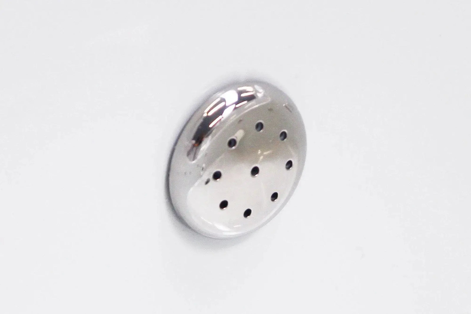 Close-up of a small, circular metal vent with multiple holes, mounted on a white surface. The shiny, smooth-edged vent reflects light beautifully, hinting at the meticulous craftsmanship found in Hot Tub Liverpool's Rexener Polar Wooden Hot Tub - Made in Finland installations.