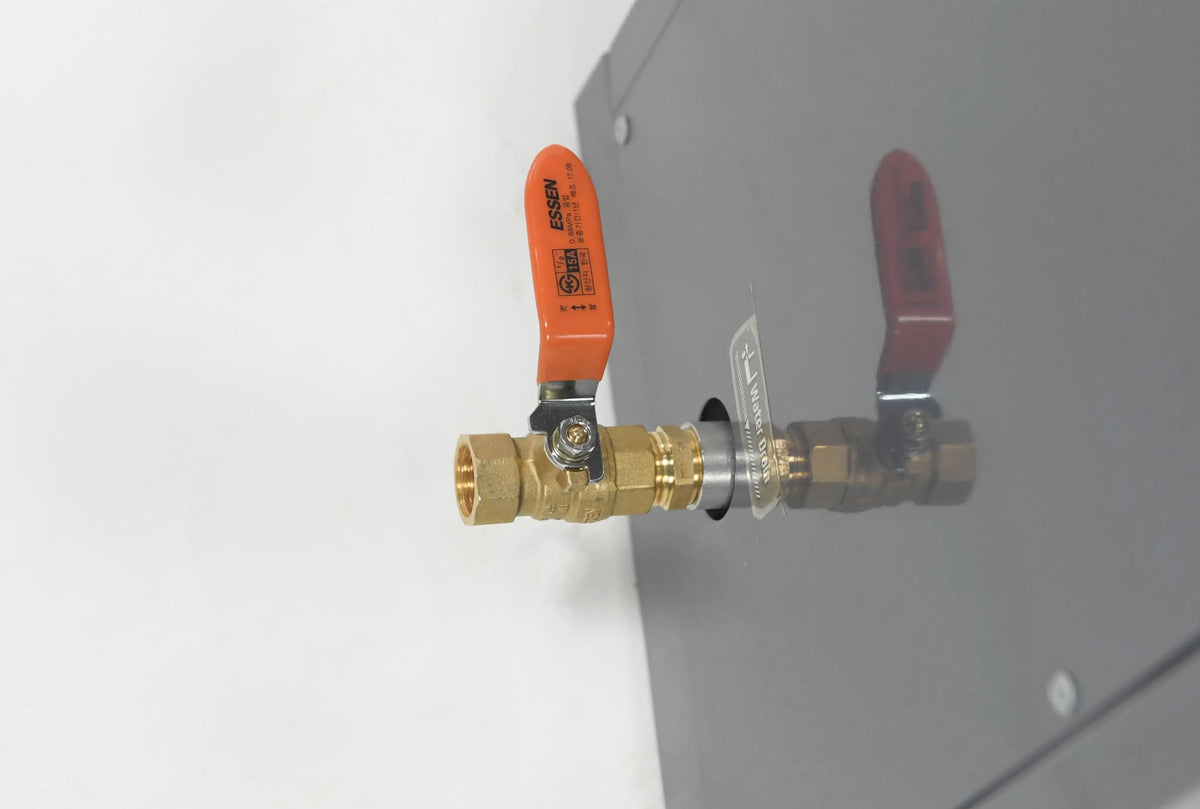 Close-up of a brass ball valve with a red handle attached to a metal panel, part of a Hot Tub Liverpool REXENER PR200 energy efficient hot tub water heater system. The valve is connected to a fitting at the base, and its reflection can be seen on the shiny surface of the panel.