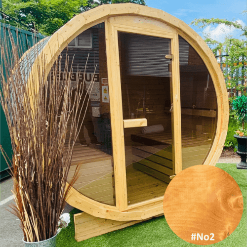 A Sunbeach Delux Moon Terrace 160 Sauna - Pre-Built with an electric Harvia heater and a glass door stands outdoors on a patch of green artificial grass. The sauna has wooden benches inside, visible through the glass. A potted plant with tall, thin branches is positioned to the left. A &quot;#No2&quot; text is on the right.

Brand Name: Sunbeach Spas