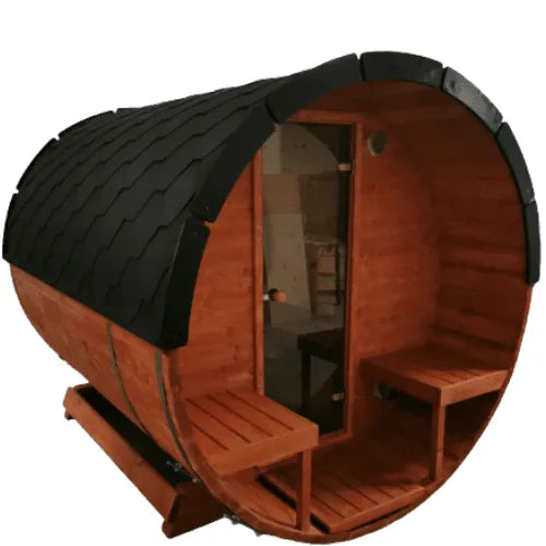 This image shows an **outdoor sauna**—the **Woodpecker 3M Lux Barrel Sauna (Pre-Built)** from **Sunbeach Spas**—crafted from alder wood, featuring a wooden barrel design with a black shingled roof. The sauna has a glass door at one end and wooden benches on either side in front of the door. An electric heater is likely inside, and the interior is visible through the door.